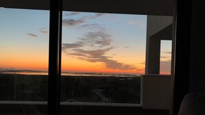 A balcony with a view of a sunset over a cityscape.