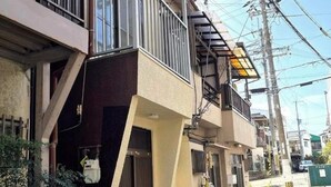 Edificio residencial con balcón, una bicicleta estacionada afuera y cables eléctricos a la vista.