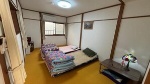 Una habitación pequeña con cama, un escritorio, una lámpara y ventana.