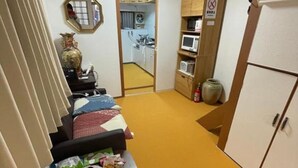 Cocina compacta con microondas, refrigerador y un armario con utensilios de cocina. Hay una pequeña mesa con alimentos y un tazón de naranjas.