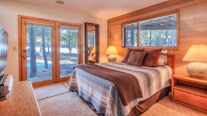 A bedroom with a large bed, two bedside lamps, a wooden headboard, and a view of the outdoors through a sliding door. - Relaxing 4BR Sunriver Retreat,Golf Views, Hot Tub, SHARC Passes, Game Room (Sunriver)