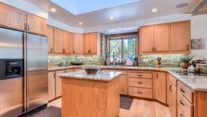 A modern kitchen with wooden cabinets, a stainless steel refrigerator, and a skylight. - Relaxing 4BR Sunriver Retreat,Golf Views, Hot Tub, SHARC Passes, Game Room (Sunriver)