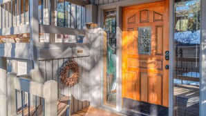 A wooden front door with a glass panel, a wooden staircase, and a wreath on the wall. - Relaxing 4BR Sunriver Retreat,Golf Views, Hot Tub, SHARC Passes, Game Room (Sunriver)