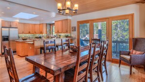 A spacious kitchen with wooden cabinets, a central island, and a dining area with a large wooden table and chairs. - Relaxing 4BR Sunriver Retreat,Golf Views, Hot Tub, SHARC Passes, Game Room (Sunriver)
