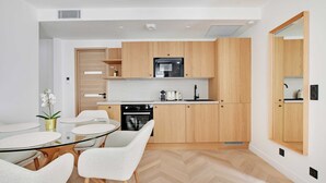 A modern kitchen with wooden cabinets, a glass dining table, and white chairs. - Charming Apartment - AC- 3br-6p- Montorgueil (Paris)