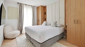A modern bedroom with a large bed, a wooden wardrobe, a built-in bench, and a wall-mounted TV. - Charming Apartment - AC- 3br-6p- Montorgueil (Paris)