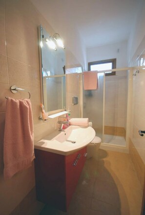 Ein Badezimmer mit Waschtisch, Spiegel und Dusche.