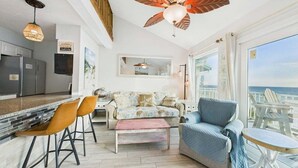 Una sala moderna con un sofá, sillones, una mesa de centro y vista al océano.