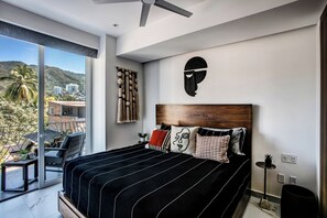 Une chambre moderne avec un grand lit, une tête de lit en bois et une vue sur la ville grâce à de grandes fenêtres.