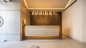 Un área de recepción moderna con un mostrador de madera, un diseño de pared estampado y una lámpara colgante.