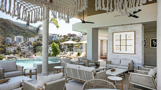 Un lounge en la azotea con piscina, mobiliario exterior y vistas a la ciudad.