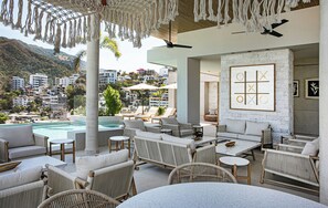 A rooftop lounge with a pool, outdoor seating, and a view of the city. - D'Vine, Romantic Zone Chic 2BR, Rooftop Pool/Oasis (Puerto Vallarta)