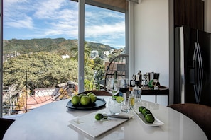 Enjoy a panoramic view of the hilly landscape from this room's large window, where you can dine on a table set with fresh fruit and wine.