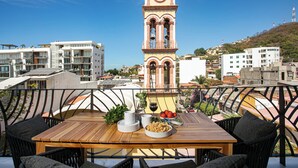 Comedor con mesa lista para dos, con vistas a un paisaje urbano que incluye edificios modernos y una torre de reloj destacada.