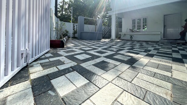 A courtyard with a checkered floor, a white building with a door, and a staircase leading to a balcony.