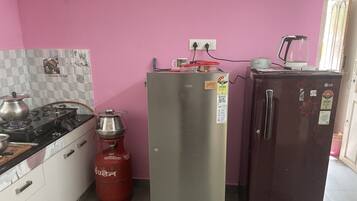 A kitchen with a gas stove, a refrigerator, and a gas cylinder.