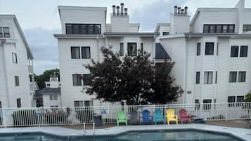 Ein Schwimmbad mit weißem Zaun und bunten Stühlen, umgeben von weißen Gebäuden.