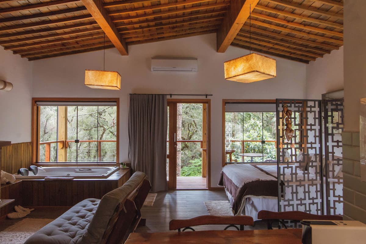 Ein geräumiges Zimmer mit großem Fenster, Holzboden und einem Bett.