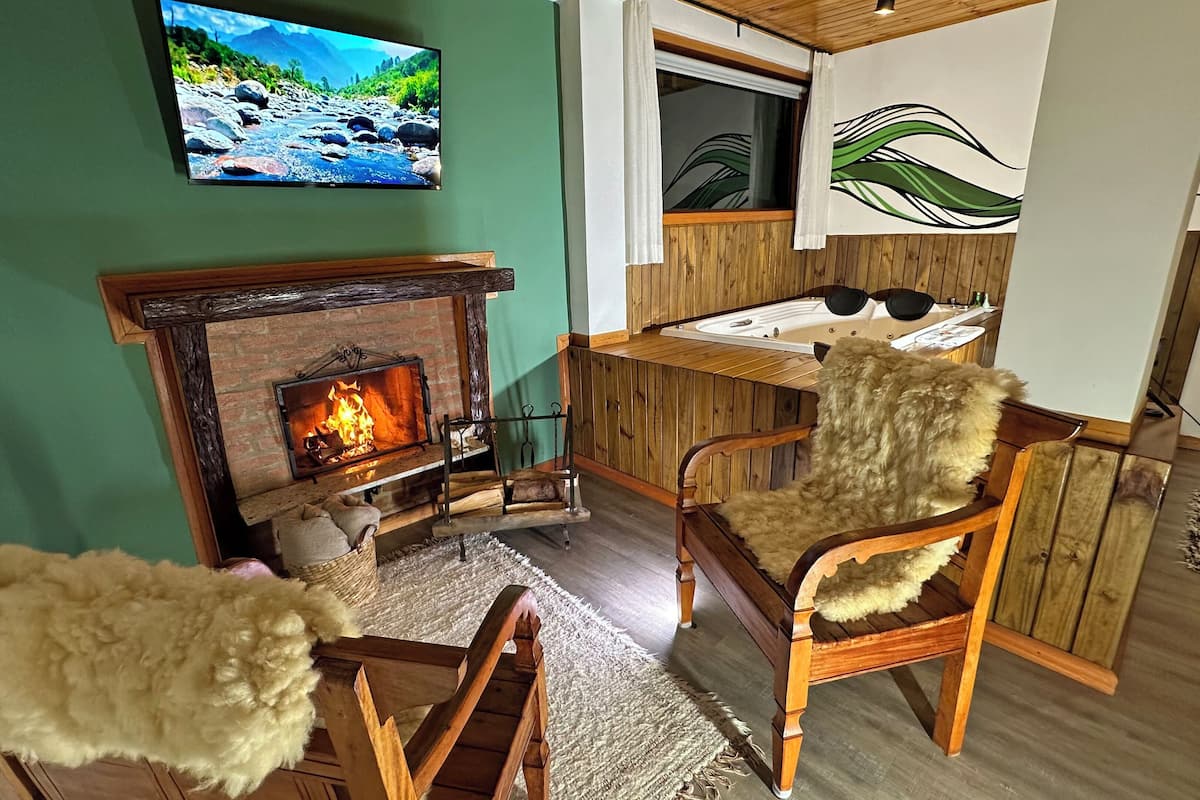 Ein gemütliches Wohnzimmer mit Kamin, Holzmöbeln und einem an der Wand befestigten Fernseher.