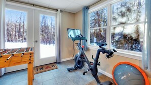 A home gym with a stationary bike, exercise bike, and a foosball table.
