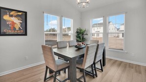 A dining area with a wooden table, four chairs, a chandelier, and a framed picture on the wall. - Serene Stay in Savannah`s Residential Heaven (Savannah)