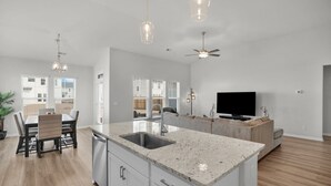 A spacious kitchen with a granite countertop, a built-in sink, and a dining area with a table and chairs. - Serene Stay in Savannah`s Residential Heaven (Savannah)