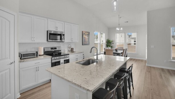 A modern kitchen with white cabinets, stainless steel appliances, a granite countertop, and a bar area with stools. - Serene Stay in Savannah`s Residential Heaven (Savannah)