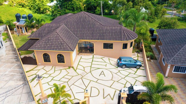 A residential house with a tiled roof, a driveway marked with 'A' and 'DW', and a parked car. - Cozy 1-bedroom apartment in charming Mandeville with WiFi, AC (Mandeville)