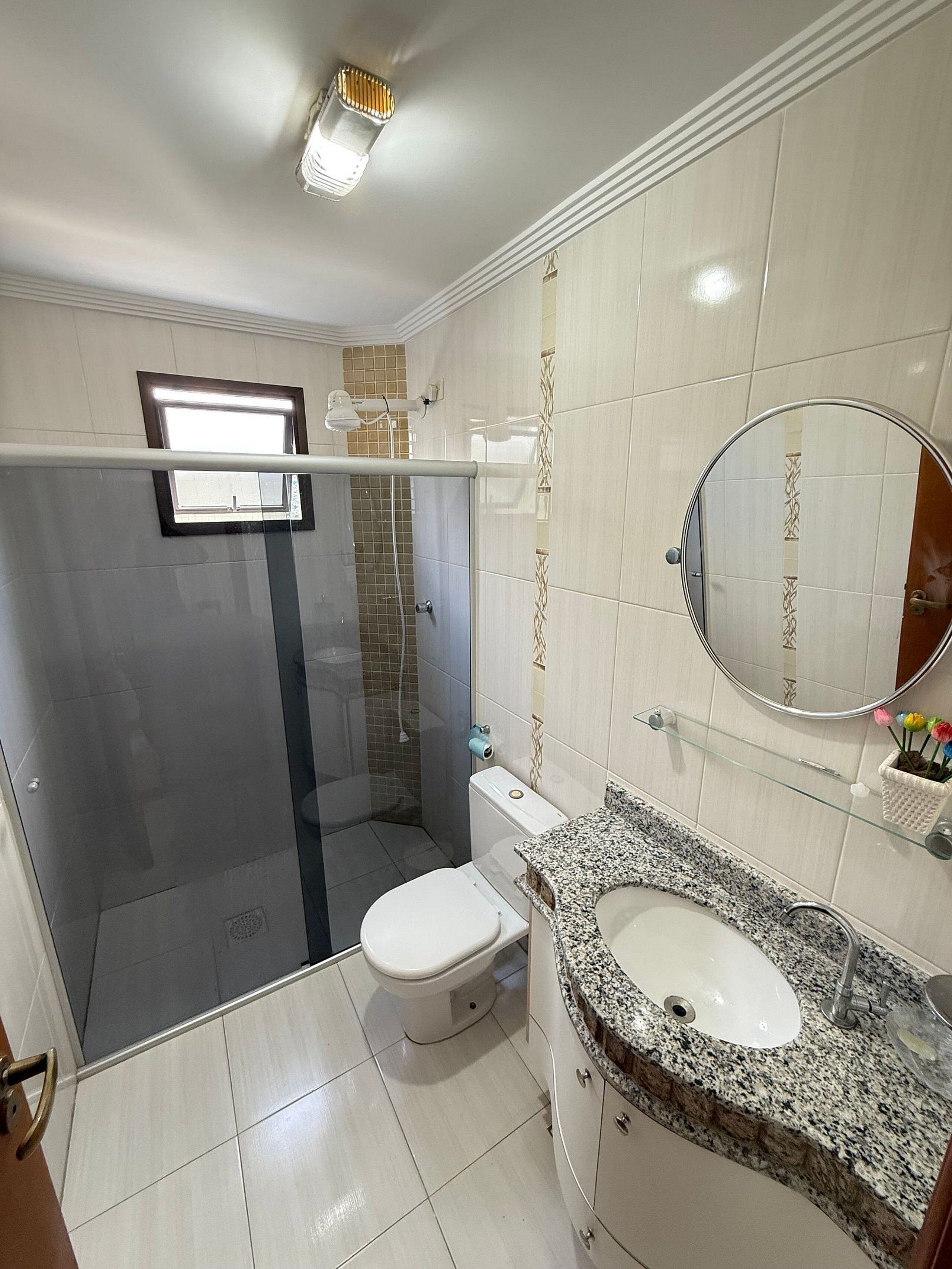 Une salle de bain équipée d’une douche, de toilettes, d’un lavabo et d’un miroir.