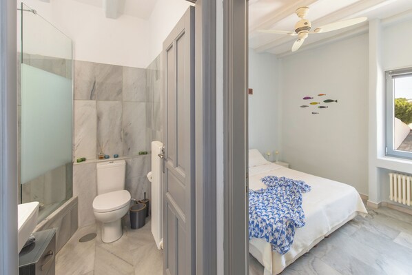 Un baño moderno con inodoro, ducha y cabina de ducha de vidrio.
