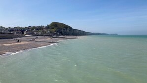A coastal beach with a rocky shoreline, a promenade, and buildings in the background. - Apartment le Beluga - near the sea - center of Veules-Les-Roses (Veules-les-Roses)