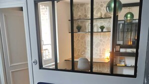A room with a dark blue sofa, a window with a black frame, and a wall with patterned wallpaper. - Apartment le Beluga - near the sea - center of Veules-Les-Roses (Veules-les-Roses)