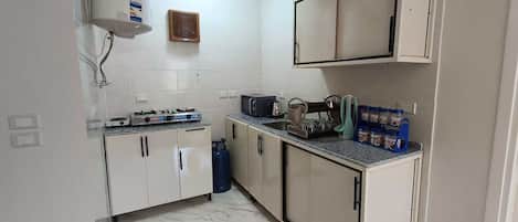 Een microgolfoven, kookgerei, borden en bestek, kruiden