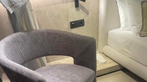 A modern living room with a grey armchair, a round black table, and a beige rug. - ASTARTE City Suite (Heraklion)