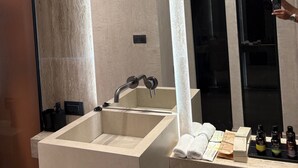 A modern bathroom with a large mirror, a built-in sink, and a vanity with toiletries. - ASTARTE City Suite (Heraklion)