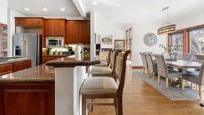 Una cocina amplia con armarios de madera, una isla central y un comedor con una mesa grande y sillas.