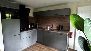 Une cuisine moderne avec des armoires grises, un plan de travail en bois et une hotte noire.