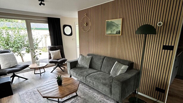 Un salon moderne avec un canapé gris, une table basse en bois et un tapis à motifs.
