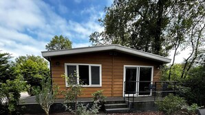 Une maison moderne avec une façade en bois, de grandes fenêtres et un patio agrémenté de paillis et de carreaux de pierre.