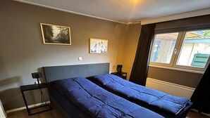Une chambre à coucher avec un grand lit, une table de chevet, une lampe et deux tableaux encadrés accrochés au mur.