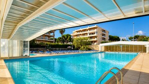 A swimming pool with clear blue water, a covered area with a roof, and a building with balconies in the background. - Villa Bono Romantic Suite & Private Jacuzzi (Saint-Laurent-du-Var)