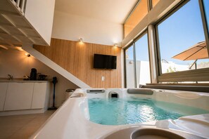 Une piscine intérieure moderne avec un mur en bois et un téléviseur fixé au-dessus.