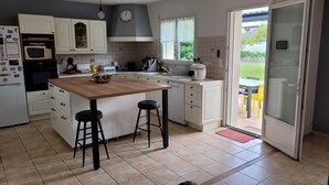 A kitchen with a central island, white cabinets, a microwave, and a dishwasher. - Bed and breakfast 15 minutes from Saumur (Vernantes)