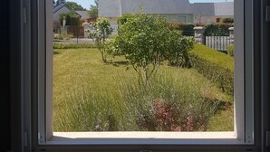 A window with a view of a well-maintained garden and a building in the background. - Bed and breakfast 15 minutes from Saumur (Vernantes)