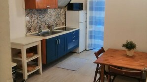 A compact kitchen with blue cabinets, a white countertop, and a small dining table with chairs.
