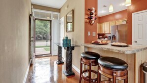 A kitchen with a bar area, a glass-top table, and wooden stools. - Relax with the whole family at this peaceful place to stay. (Memphis)