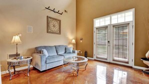 A living room with a sofa, two side tables, a decorative lamp, and a large window with blinds. - Relax with the whole family at this peaceful place to stay. (Memphis)