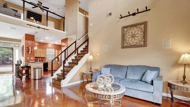 A spacious living area with a blue sofa, a glass coffee table, and a staircase leading to an upper level. - Relax with the whole family at this peaceful place to stay. (Memphis)