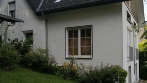 A two-story house with a sloped roof, a satellite dish, and a window with white frames. - Cozy, bright apartment in a very quiet location (Detmold)