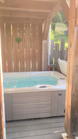 A hot tub in a wooden gazebo with a heart-shaped cutout on the wall. - LE CHALET DU PIC :PRIVATE SPA.mountain views and Mt Blanc.near Les Gets and Samoens. (Taninges)
